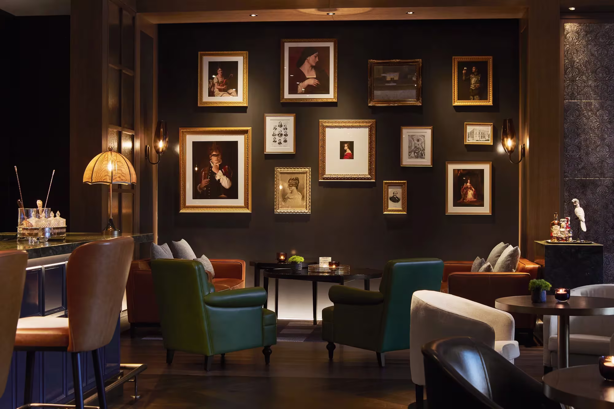 Salon des Rosewood Villa Magna in Madrid mit dunkler Porträtwand, samtenen Sesseln und warmem Lampenlicht