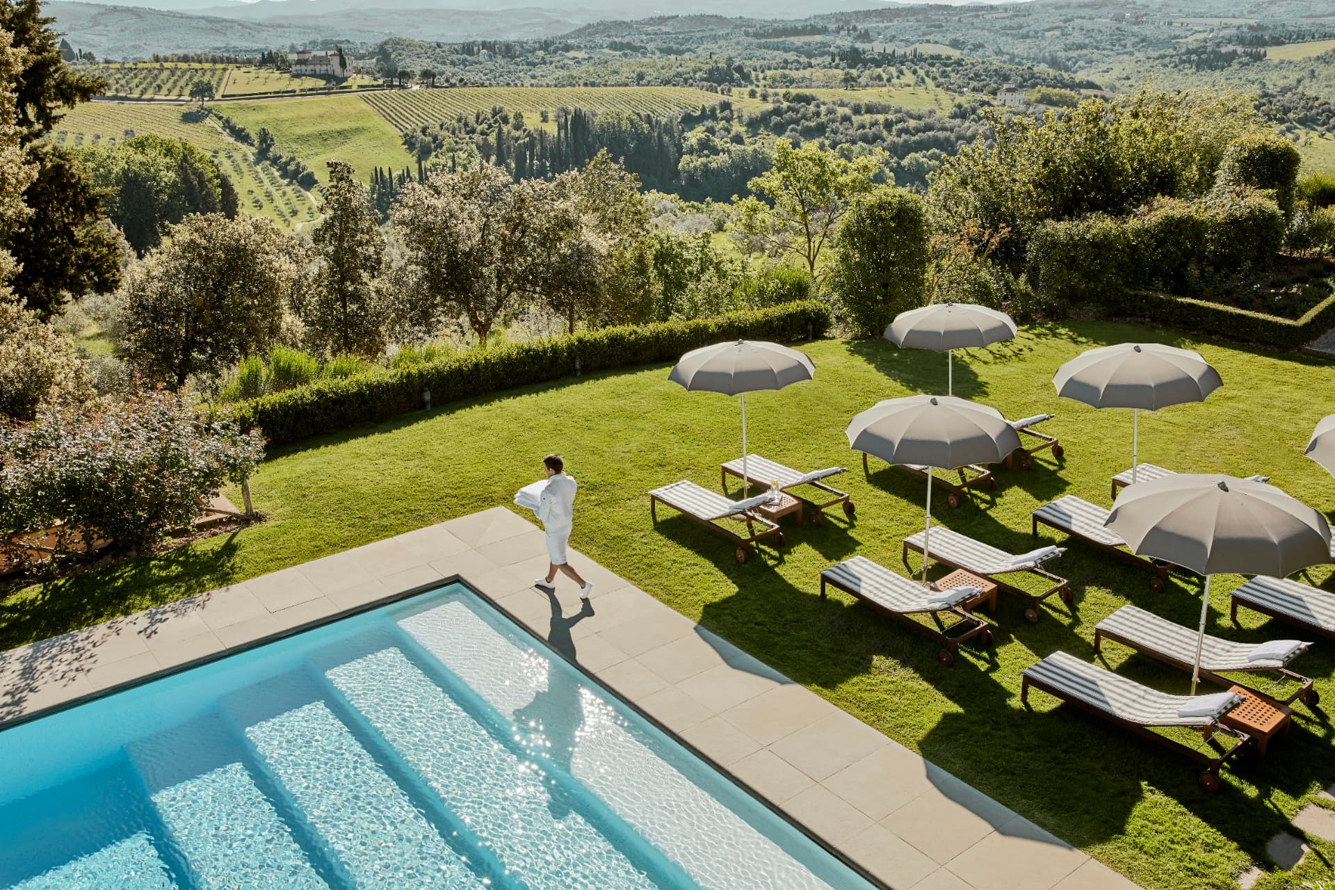Pool im Garten mit Liegen unter Sonnenschirmen über den Weinbergen