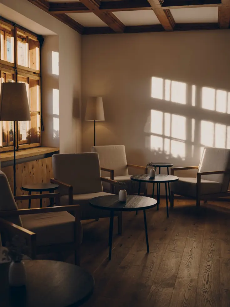 Lounge mit hellen Sesseln, Stehlampen und Lichtmustern an der Wand