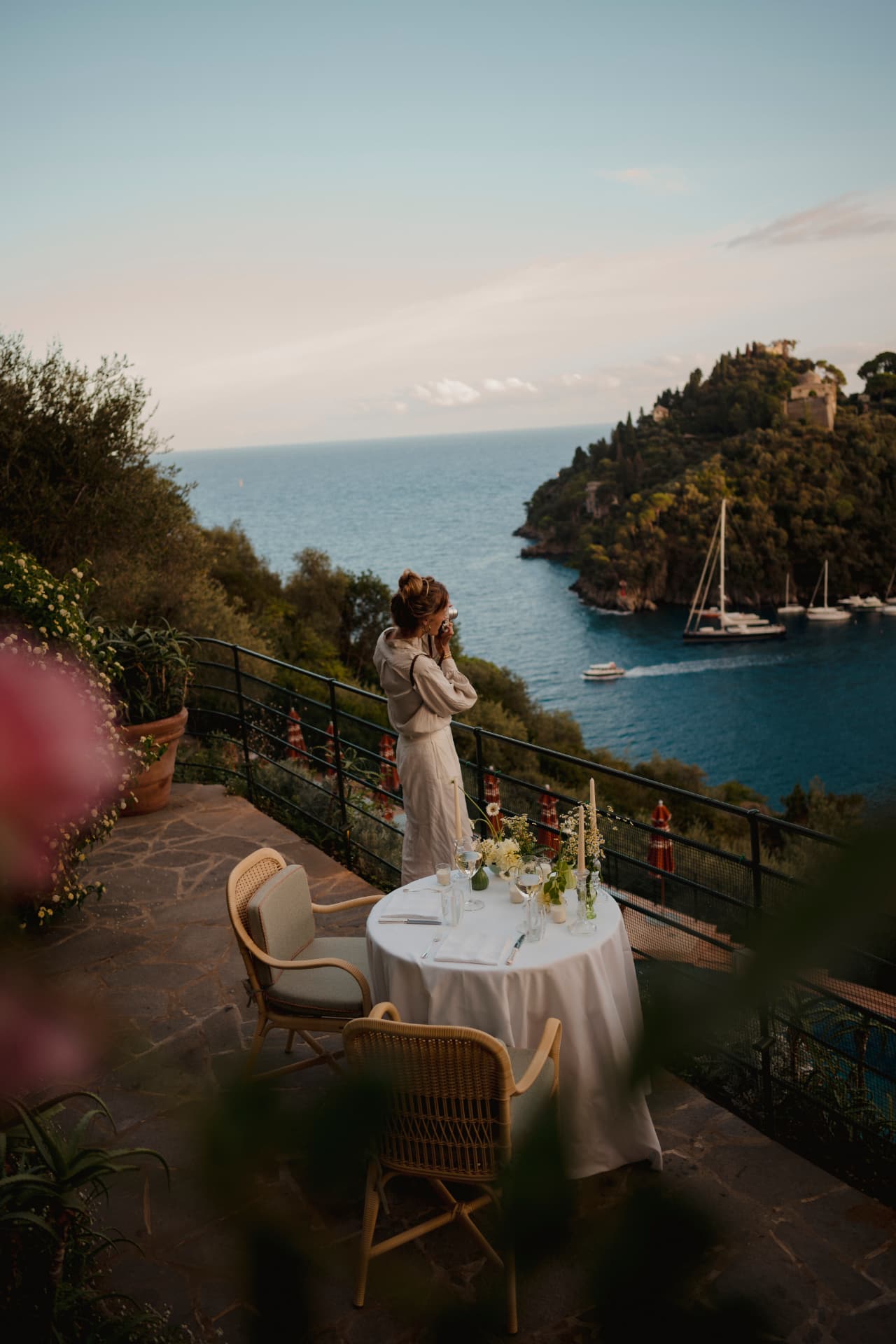 Gedeckter Tisch für zwei auf der Gartenterrasse im Abendlicht, dahinter die Bucht von Portofino mit ankernden Yachten