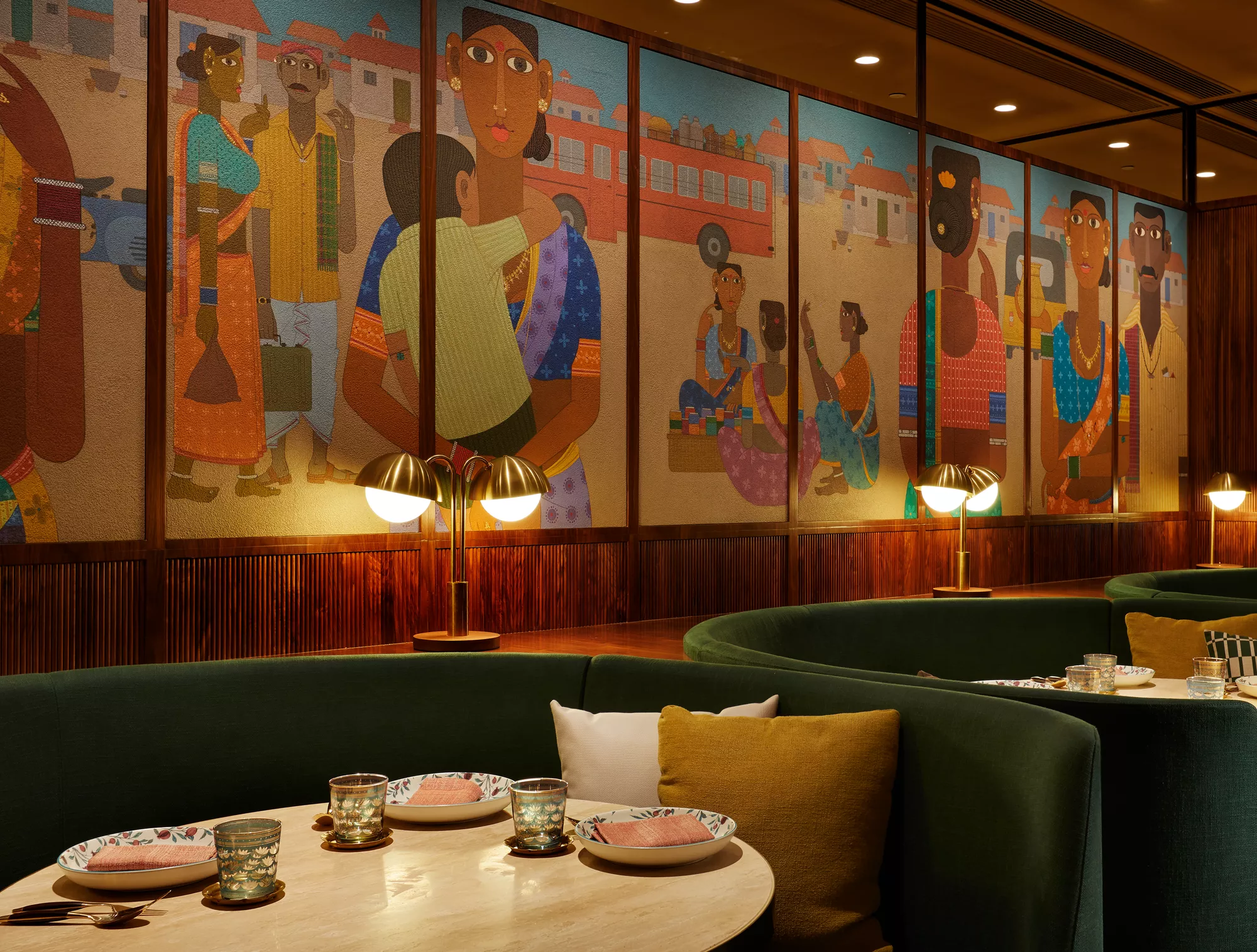 Das Restaurant CHAAT im Rosewood Hong Kong mit grünen Rundbänken, Messinglampen und einem großflächigen indischen Wandbild