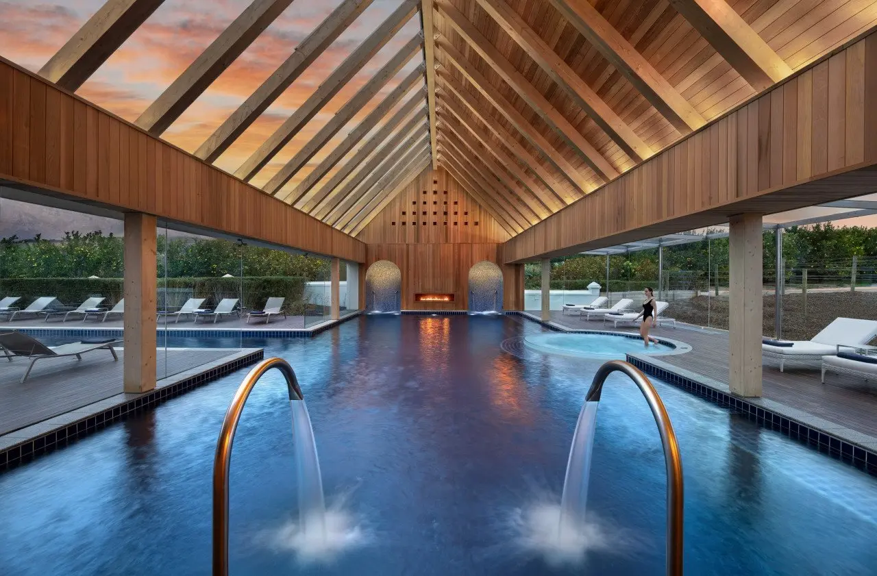 Pool des Garden Spa unter offenem Holzdach in der Dämmerung