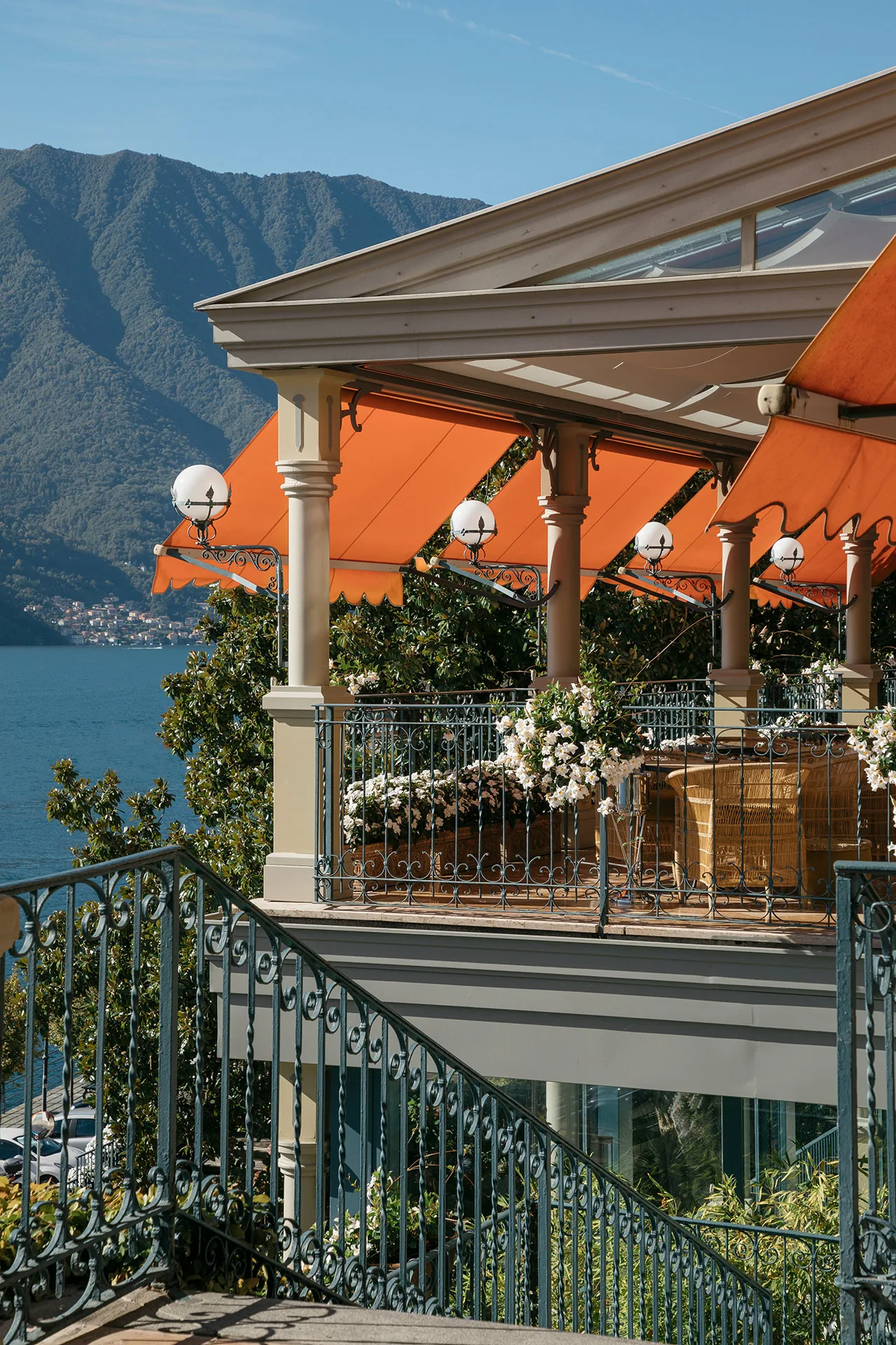 Terrasse unter orangefarbener Markise mit gedeckten Tischen über dem See
