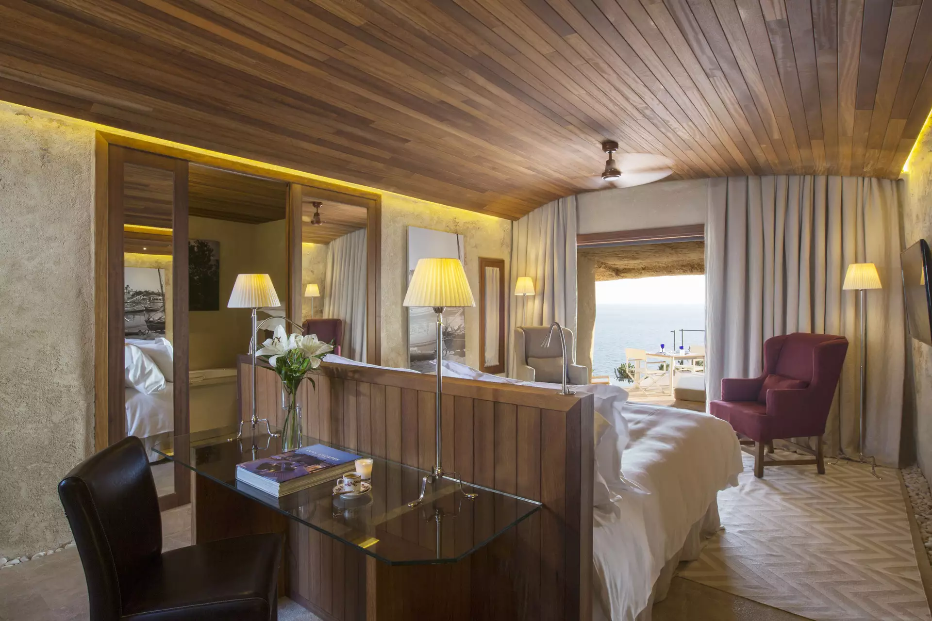 Suite mit warmer Holzdecke und raumhohem Blick auf das Meer