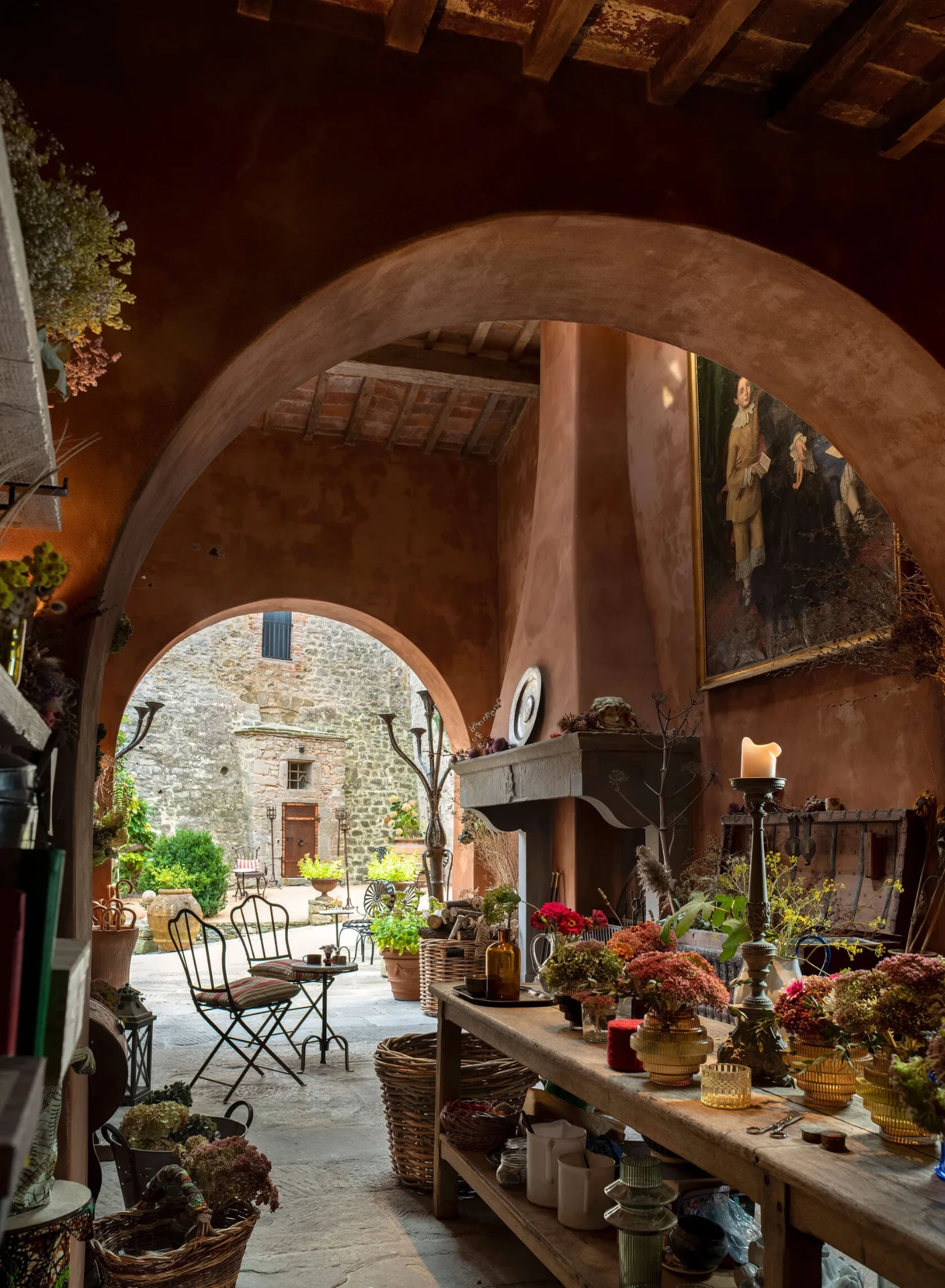 Blumenzimmer unter Terrakottabögen mit Werkbank, Vasen und Blick in den Innenhof