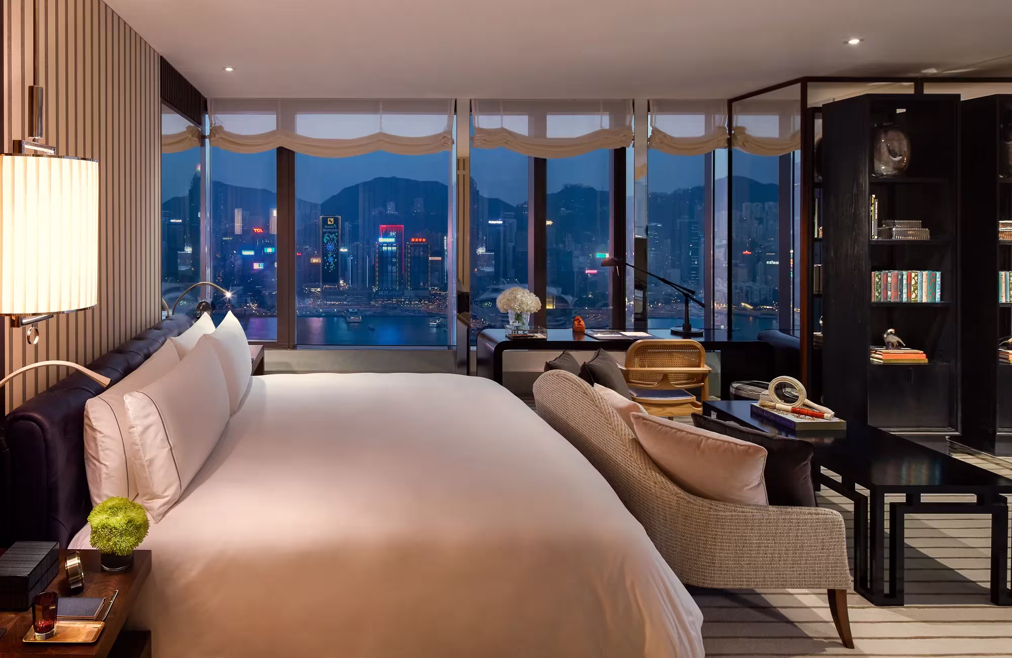 Schlafzimmer einer Ein-Schlafzimmer-Residenz im Rosewood Hong Kong mit Holzpaneelen, Leseecke und Fensterfront