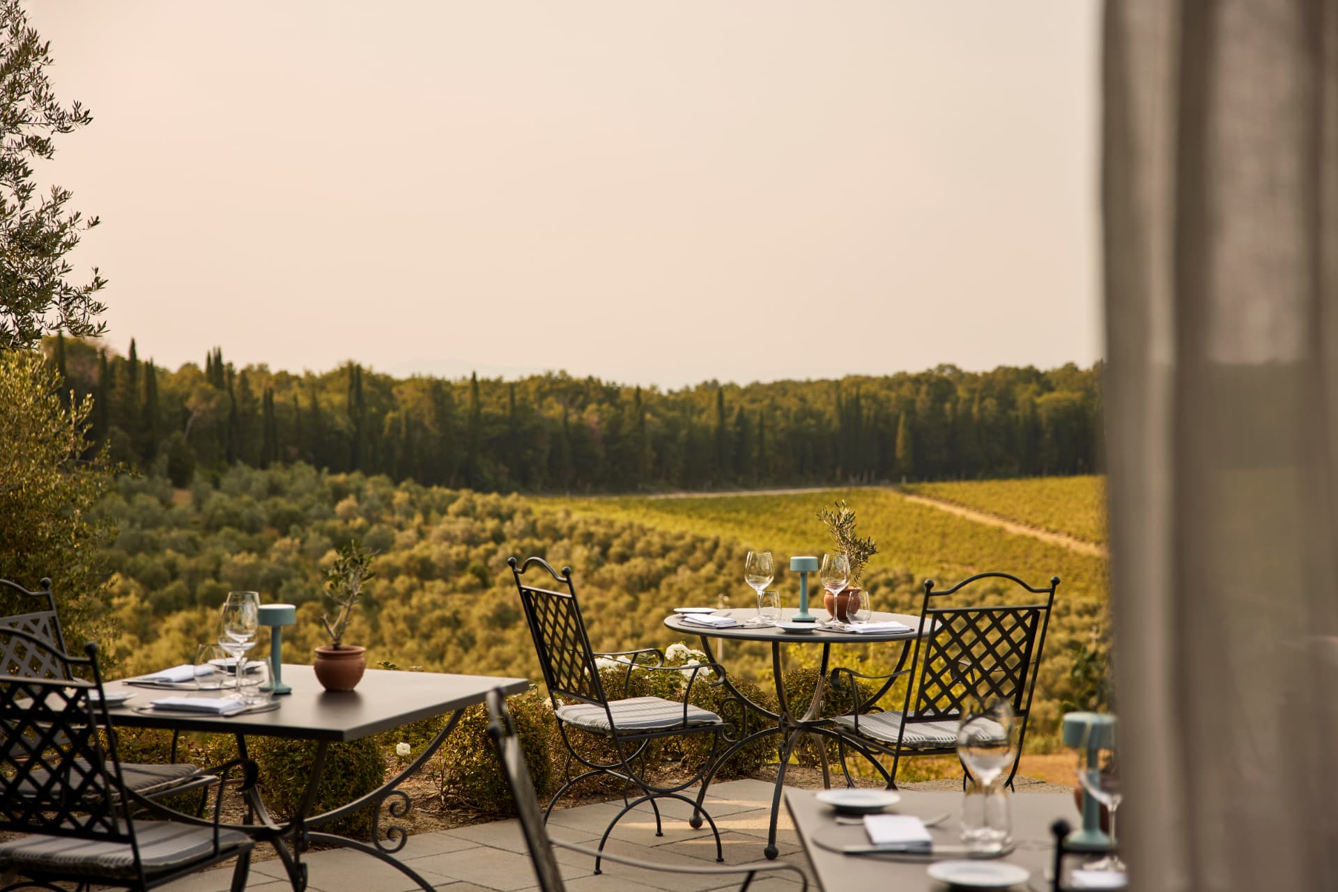 Gedeckte Tische auf der Terrasse mit Blick über Olivenhain und Weinberg