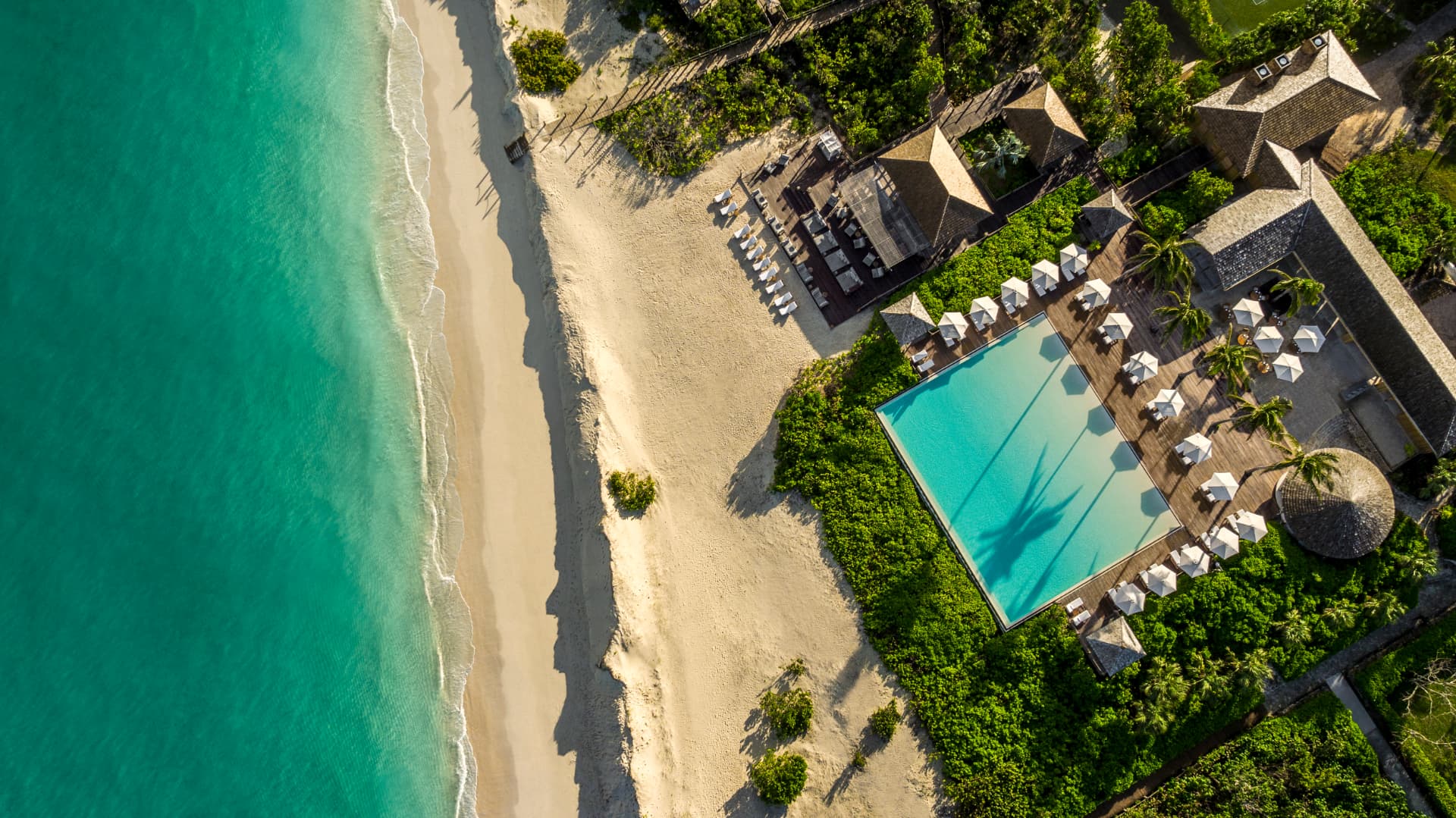COMO Parrot Cay von oben: Beach Club, Pool und der lange weiße Strand an der türkisen Karibik