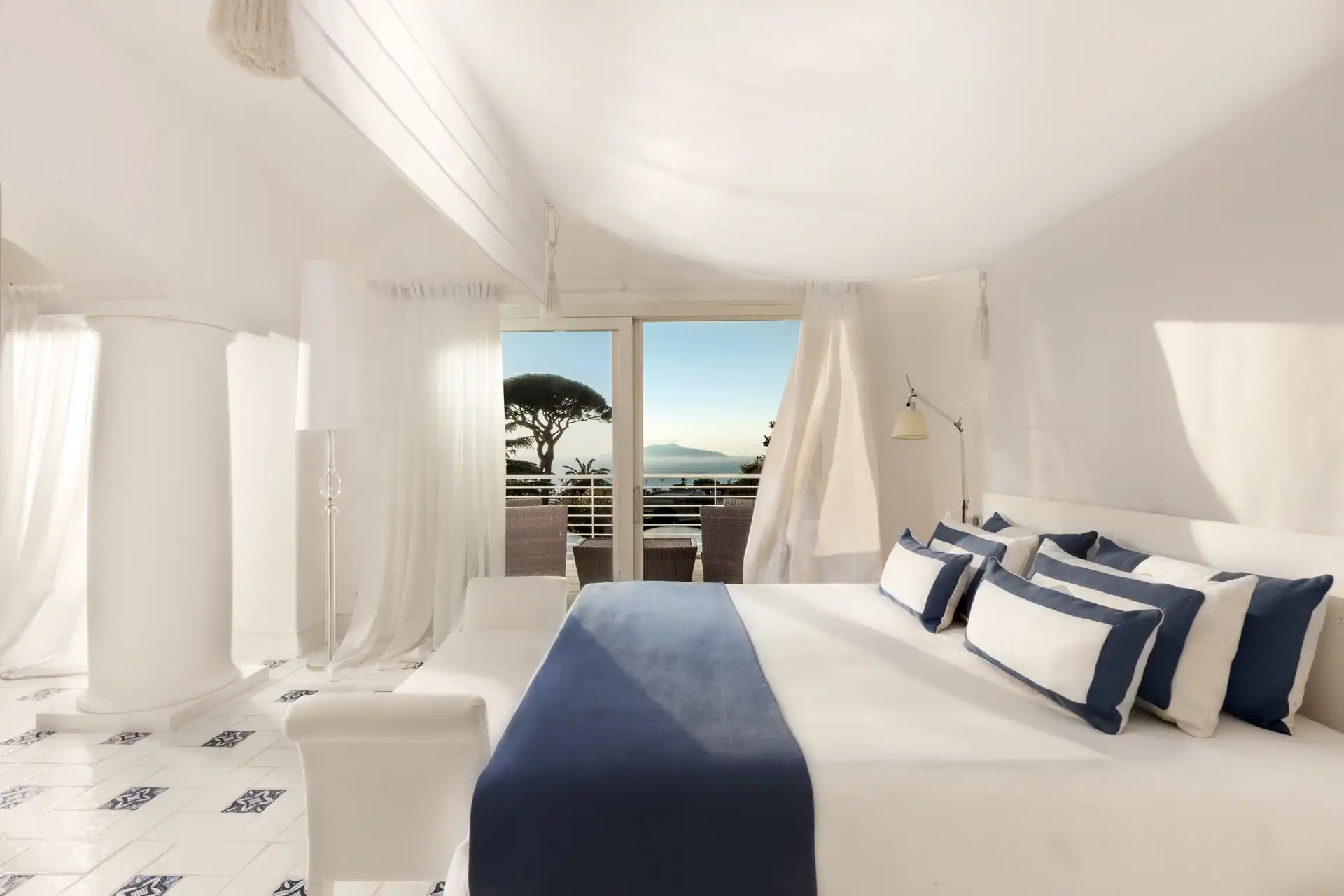 Weißes Schlafzimmer mit blauen Kissen und Terrassentür zum Golf von Neapel