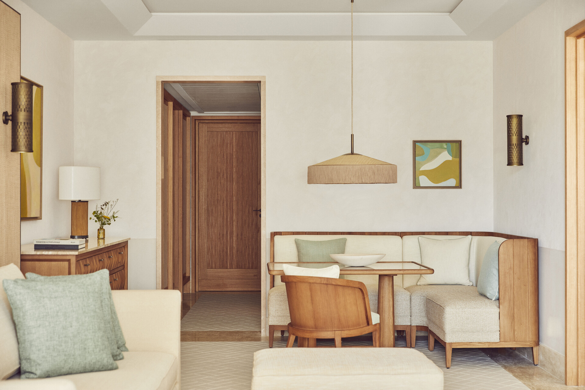 Wohnbereich einer Suite mit Eichenbank, hellen Textilien und Rattanleuchte