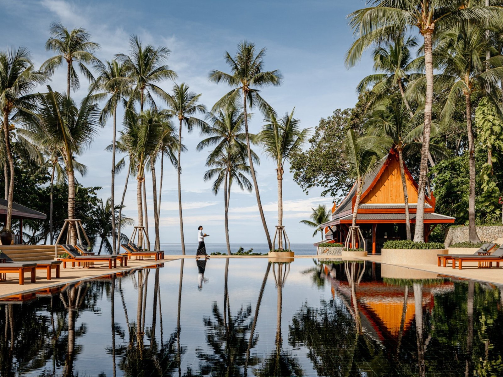 Der schwarze Hauptpool des Amanpuri, gesäumt von Kokospalmen und Pavillons, mit Blick auf die Andamanensee