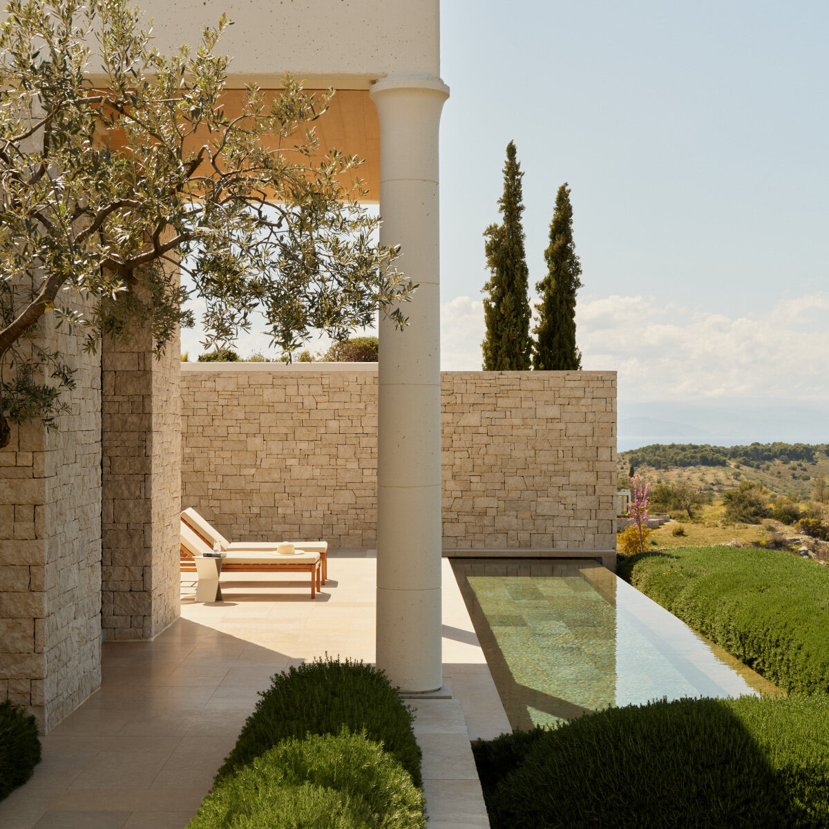 Deluxe Pool Pavilion in Amanzoe mit Olivenbaum, Kalksteinmauer und schmalem privatem Pool über den Hügeln der Argolis