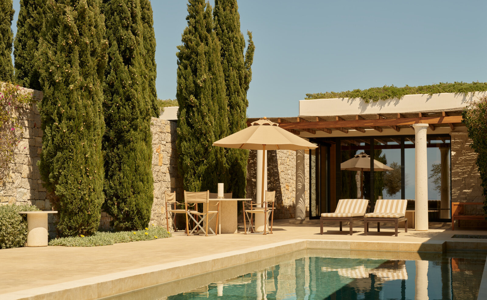 Cabana am Beach Club von Amanzoe mit privatem Pool, Sonnenschirm, Zypressen und einer Natursteinmauer