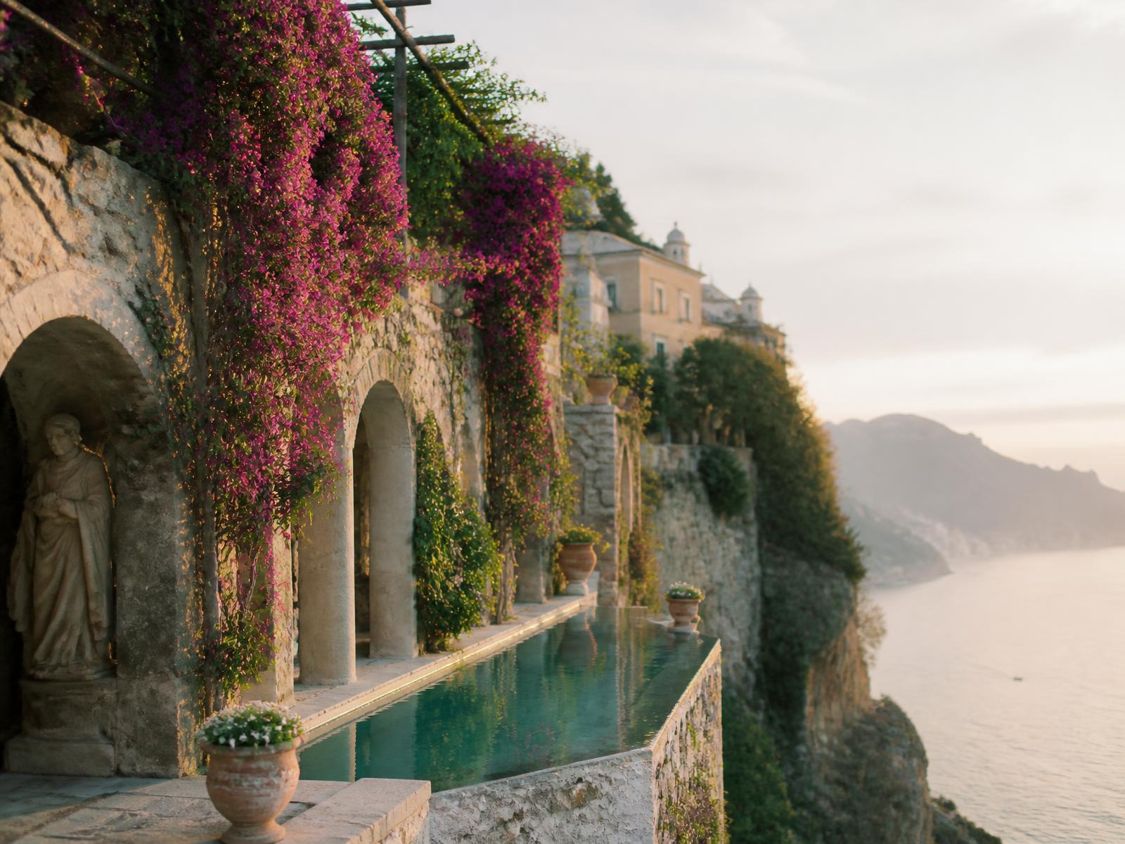 Ancient cliffside terrace with stone arches, bougainvillea and an infinity pool above the Amalfi coastline