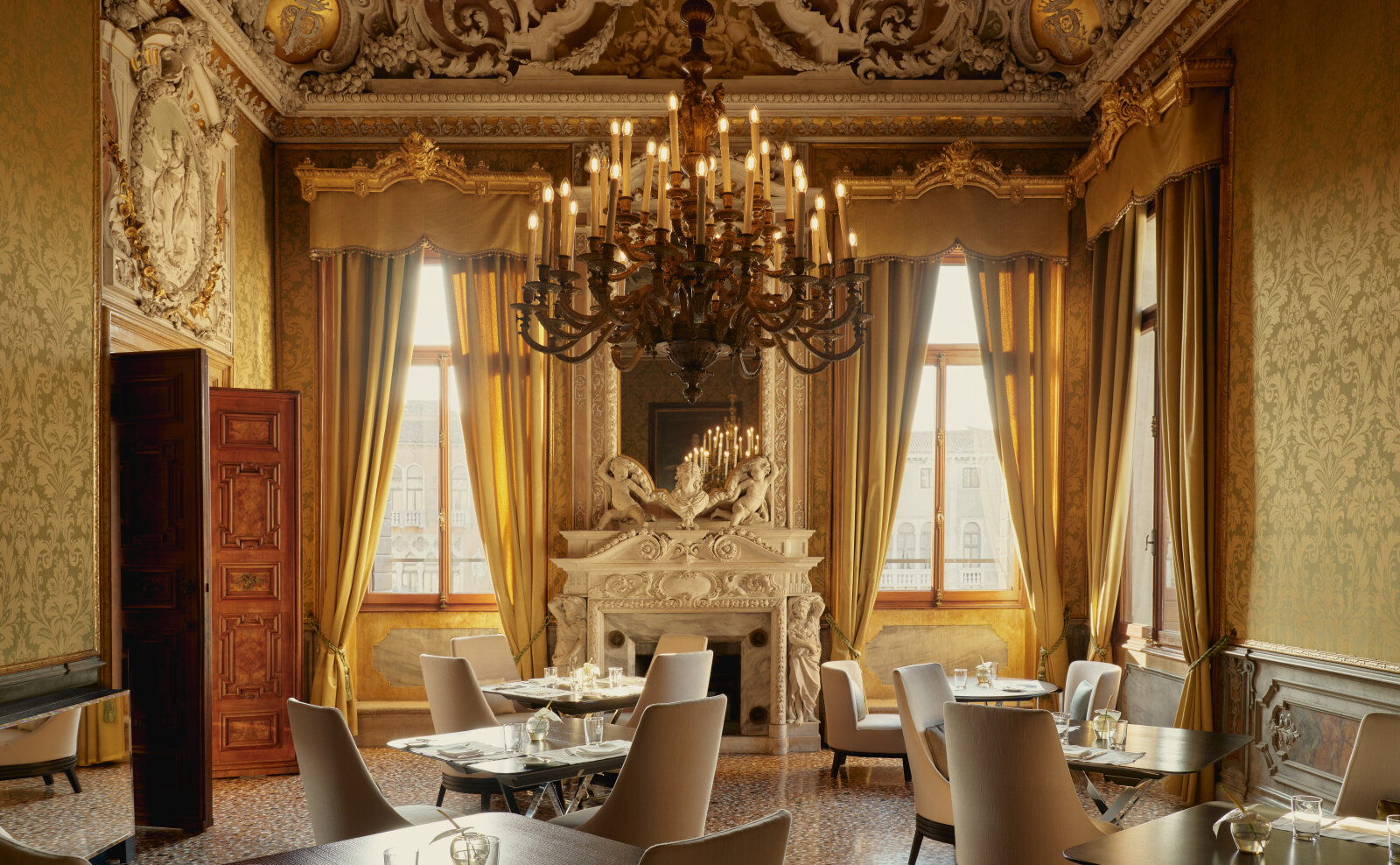 Einzelner Tisch mit weißem Leinen und Glas in einem freskierten venezianischen Speisesaal, Kerzenlicht