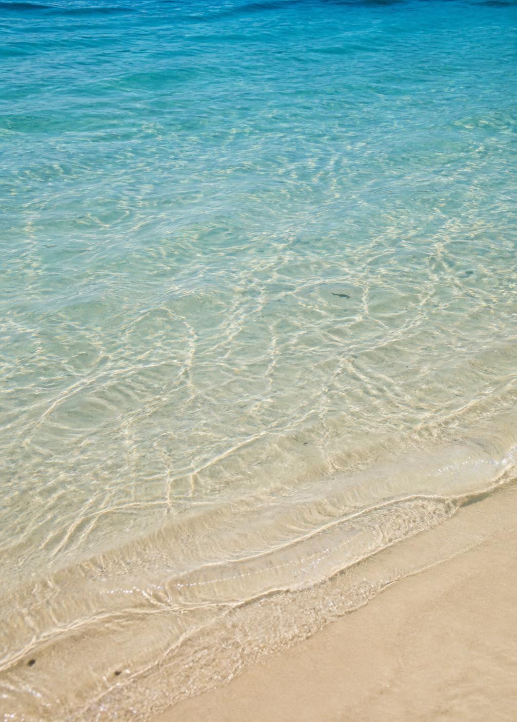 Clear shallow turquoise water over white rippled sand with sunlight caustics