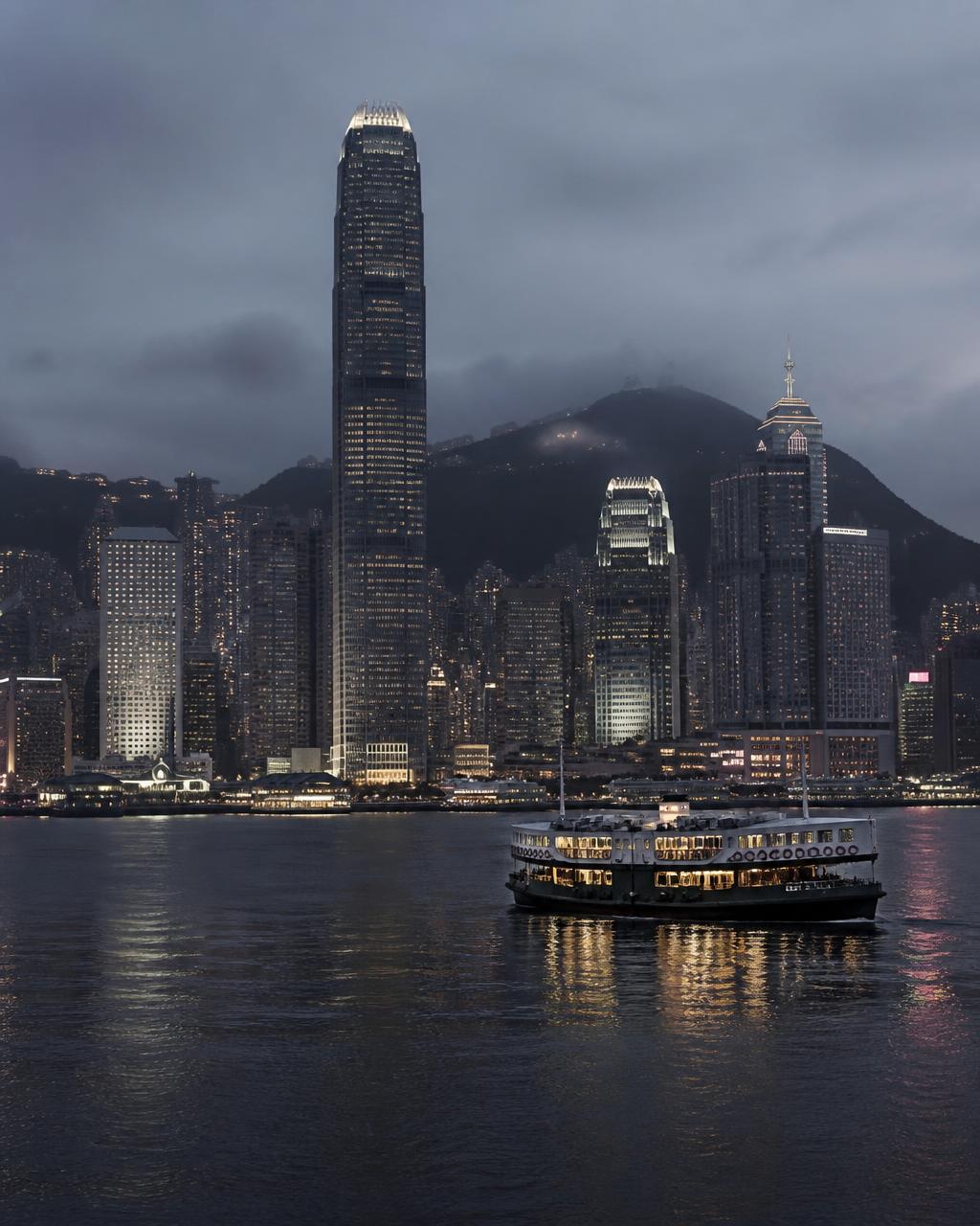 Victoria Harbour at blue hour from the Kowloon waterfront with the Hong Kong Island skyline reflected on still water and a lit Star Ferry crossing