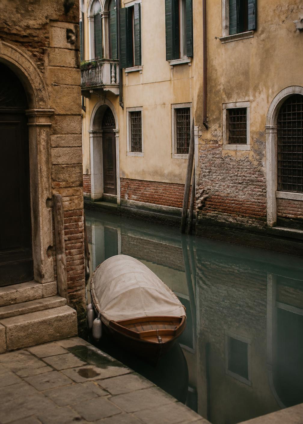 Narrow Venetian side canal at first light with a single moored boat under a linen cover