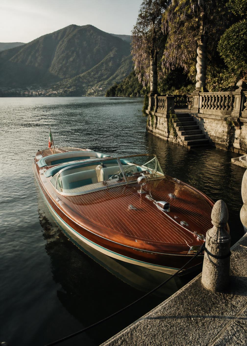 Classic mahogany Riva motorboat moored at a private stone pier on Lake Como in late afternoon light