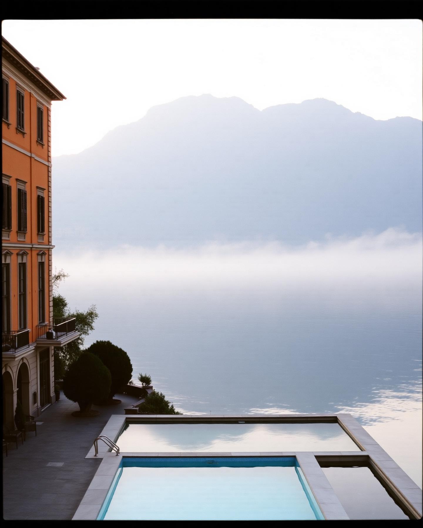 Belle-Époque-Hotel am Comer See im Morgennebel mit schwimmendem Pool auf dem Wasser