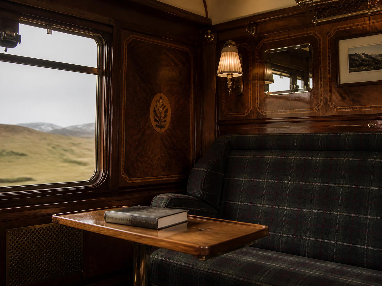 Edwardianisches Zugabteil-Interieur mit polierten Mahagoni-Intarsien, Tartan-Wollpolstern, Messingwandlampen und einem Fenster zur Highland-Moorlandschaft