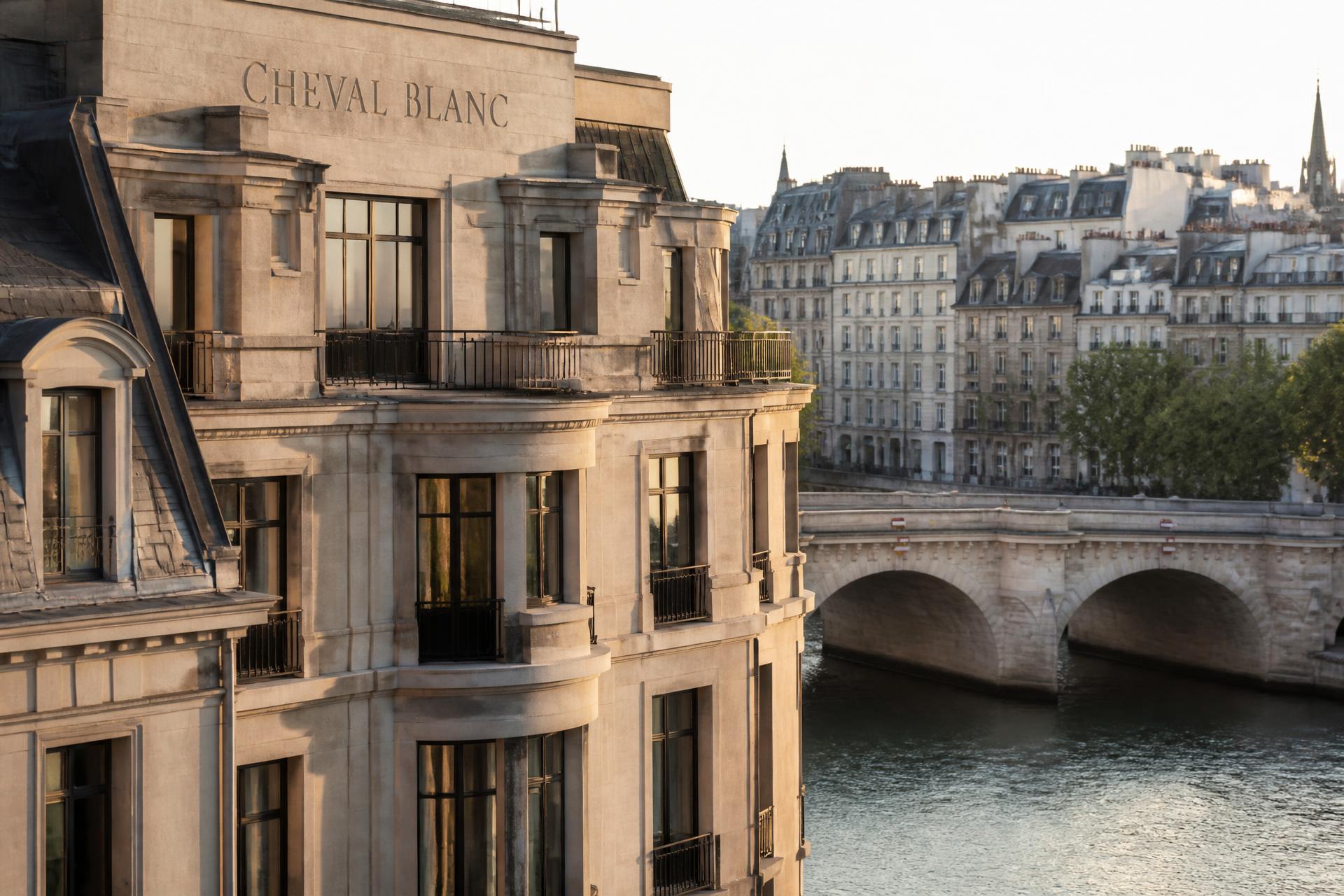 Cheval Blanc Paris limestone façade above the Seine at soft morning light with the Pont Neuf, French balconies and Parisian rooftops beyond