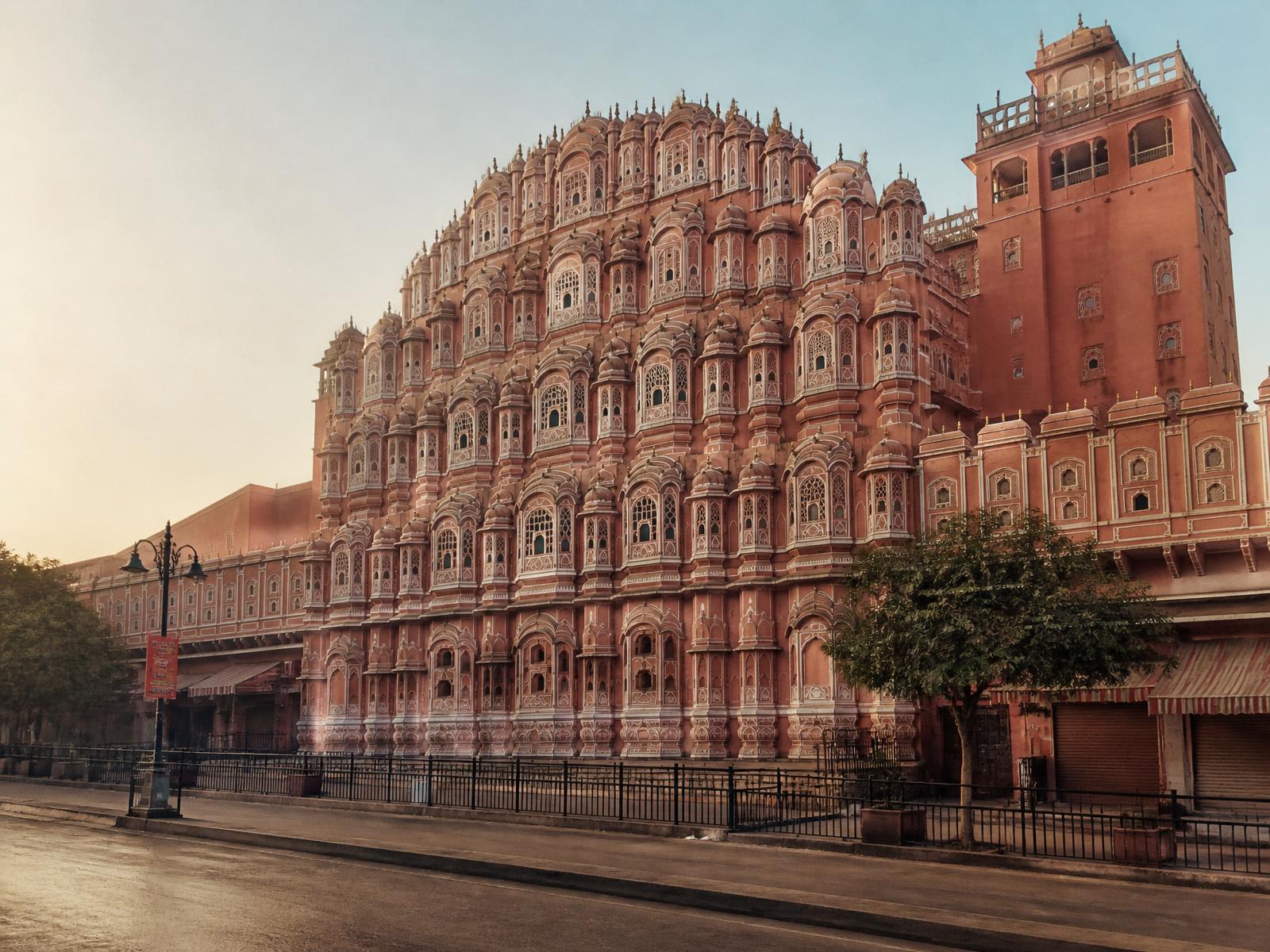 The pink sandstone facade of Hawa Mahal in Jaipur at early morning light, its lattice windows in shadow