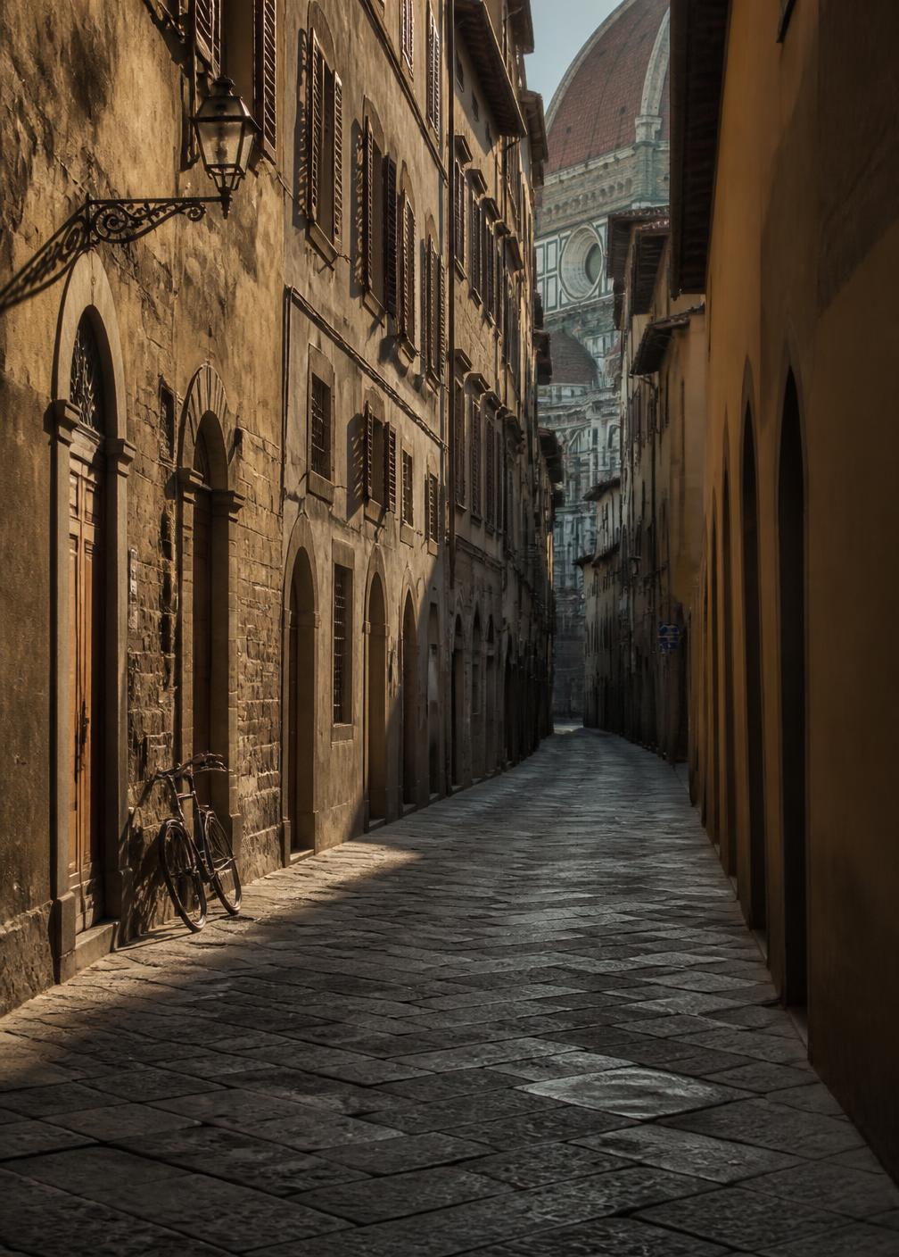 An empty narrow Florentine stone street at first light with shuttered windows and long soft shadows