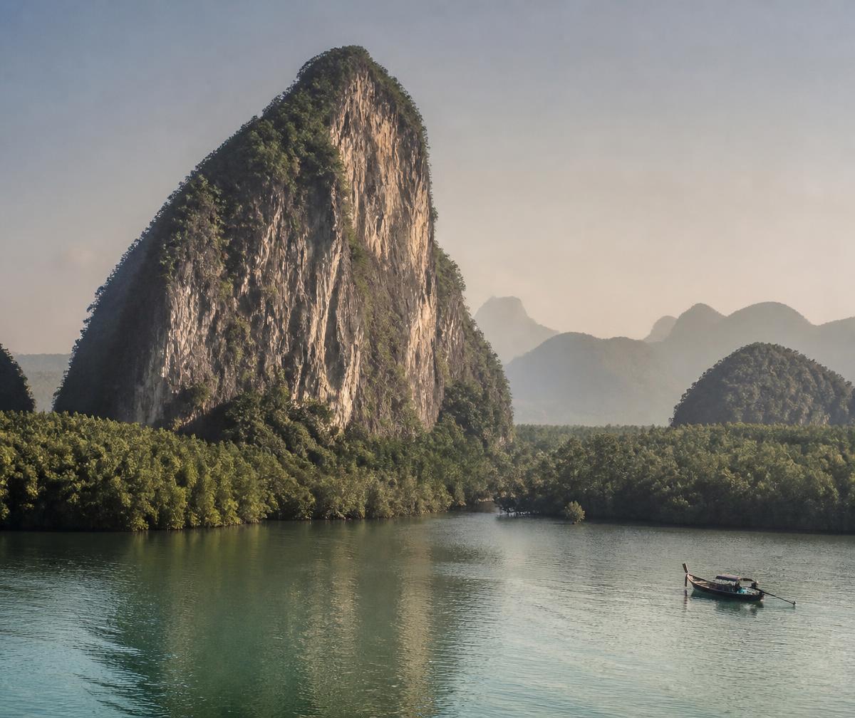 Limestone karst cliffs rising from calm turquoise water among mangrove channels in Langkawi at dawn