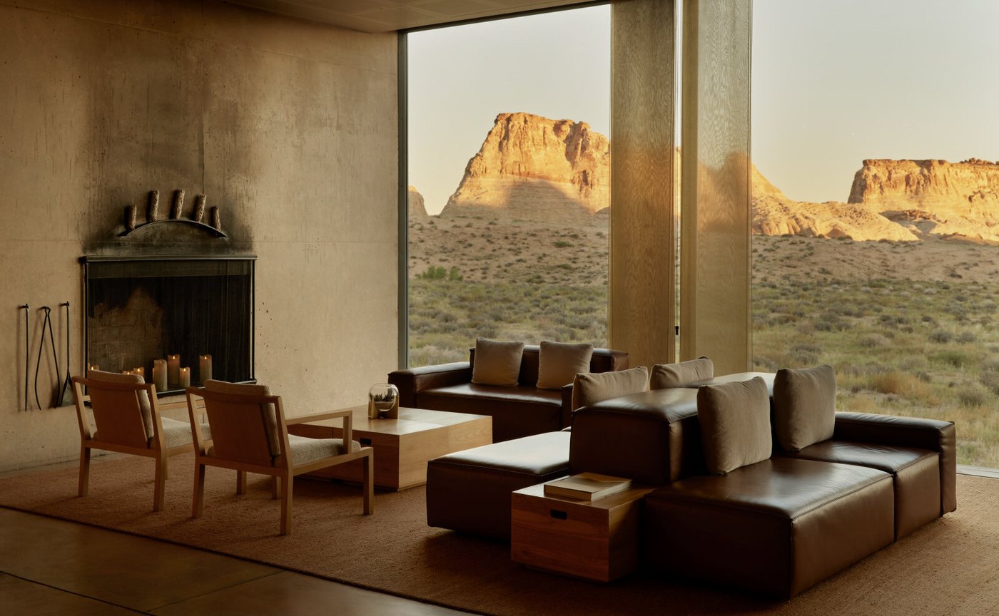 Der Hauptpavillon von Amangiri mit offenem Kamin, Ledersofas und raumhoher Verglasung, hinter der die Mesas im Abendlicht leuchten