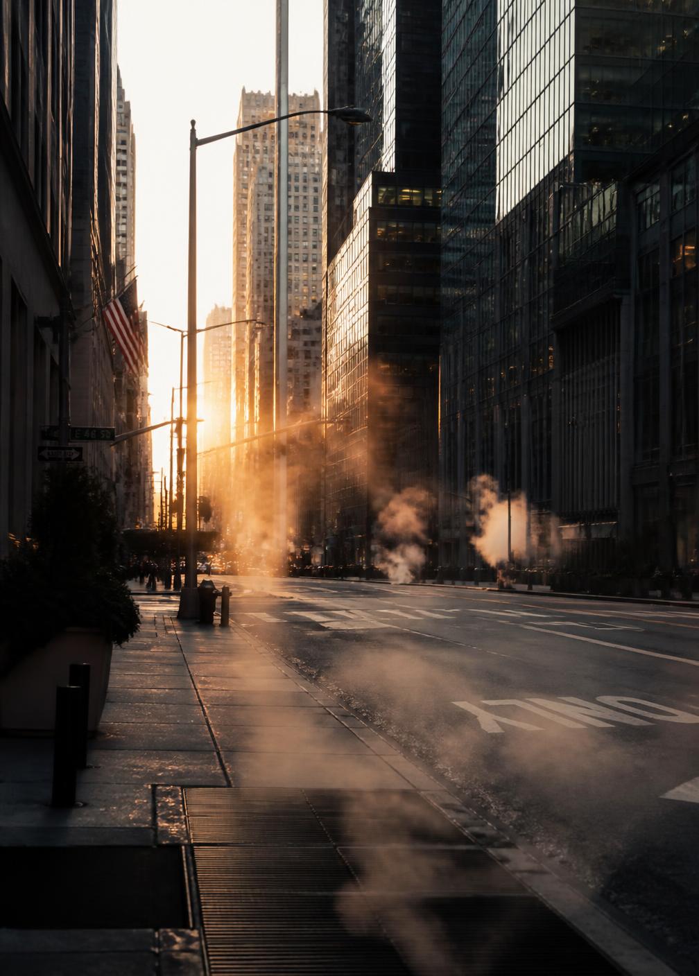 Empty Manhattan street on a cold early morning with steam rising and low sun between the buildings