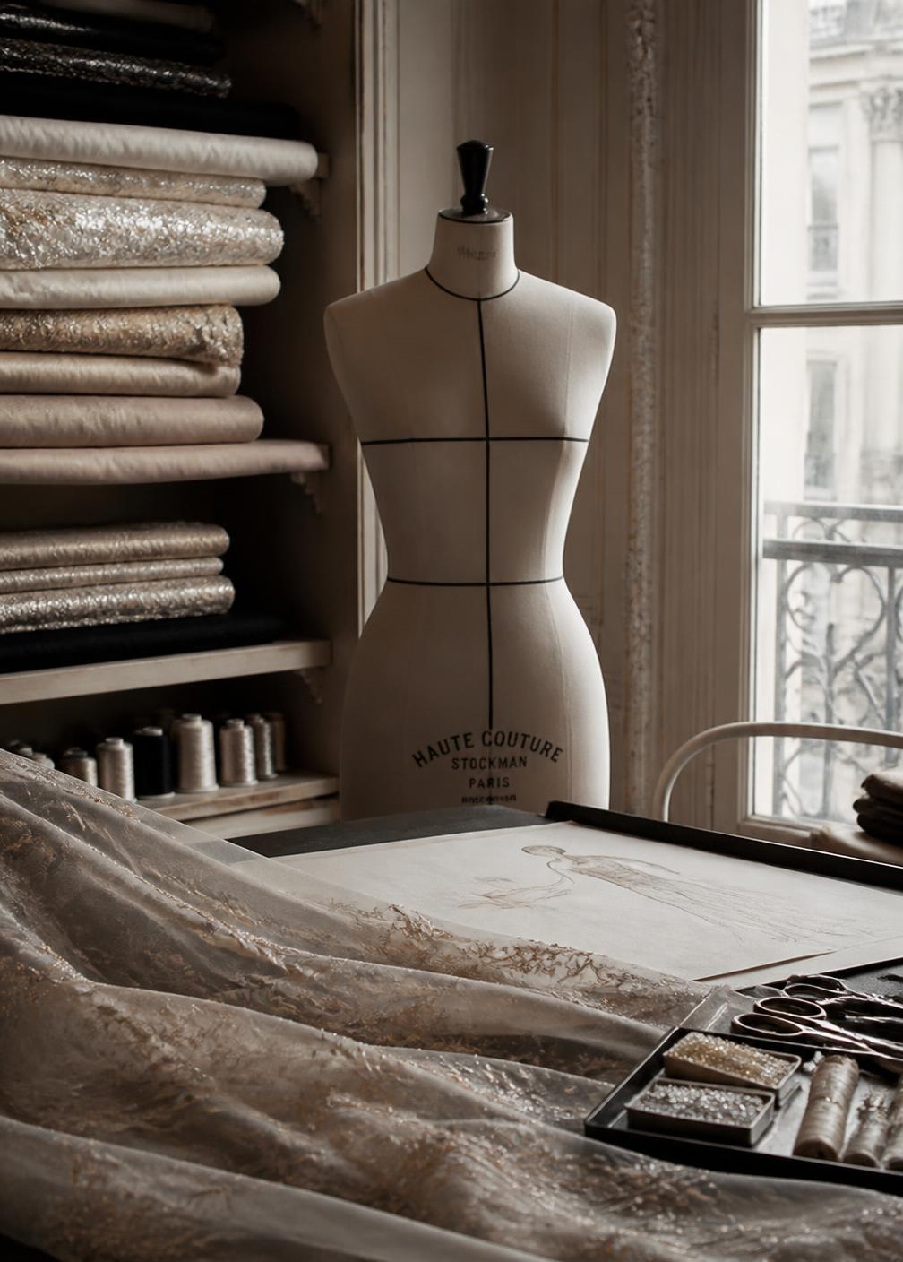 Haute couture atelier in Paris with bolts of silk, thread spools and a tailor's dummy in soft window light