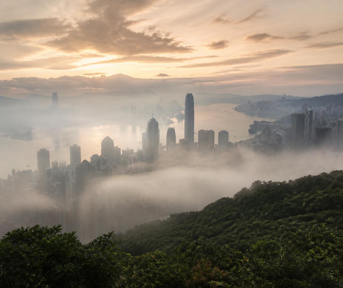 Victoria Harbour at first light seen from Victoria Peak with layered mist and the skyline emerging from cloud
