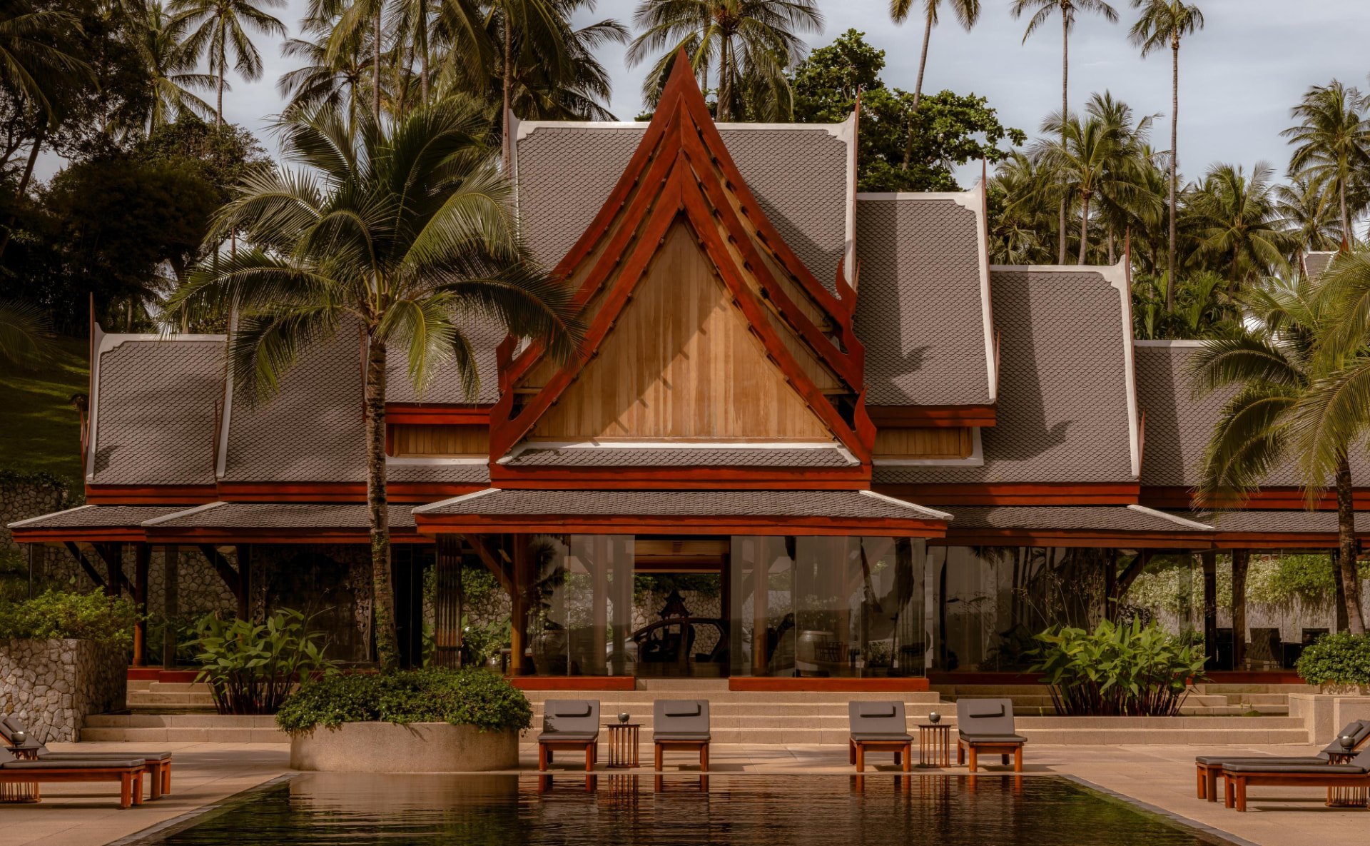 Der große thailändische Pavillon des Amanpuri mit steilem Dach, gespiegelt im dunklen Wasser des Hauptpools