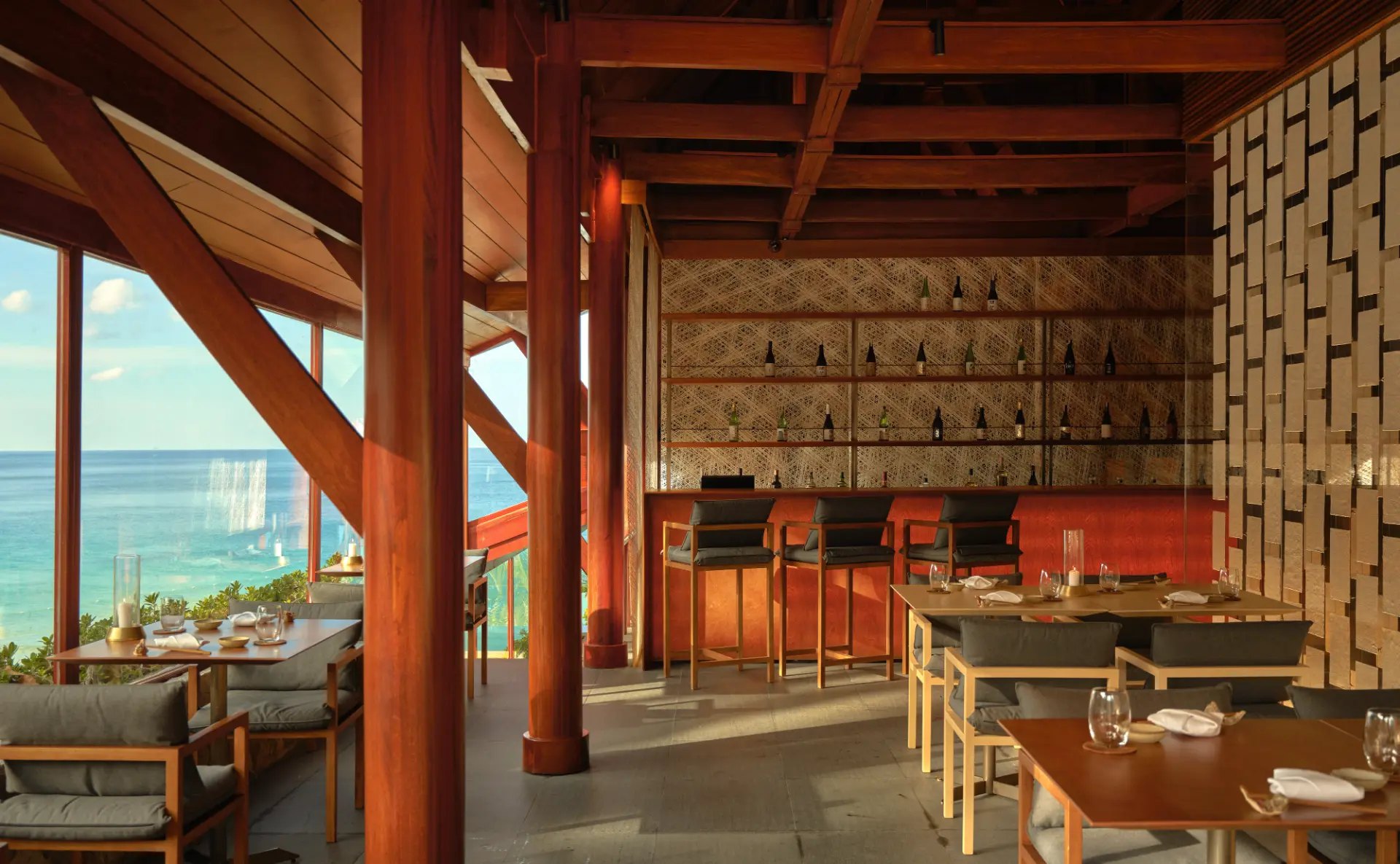 Der Speiseraum des Nama mit Holztischen, Sake-Bar und großen Fenstern zum Meer