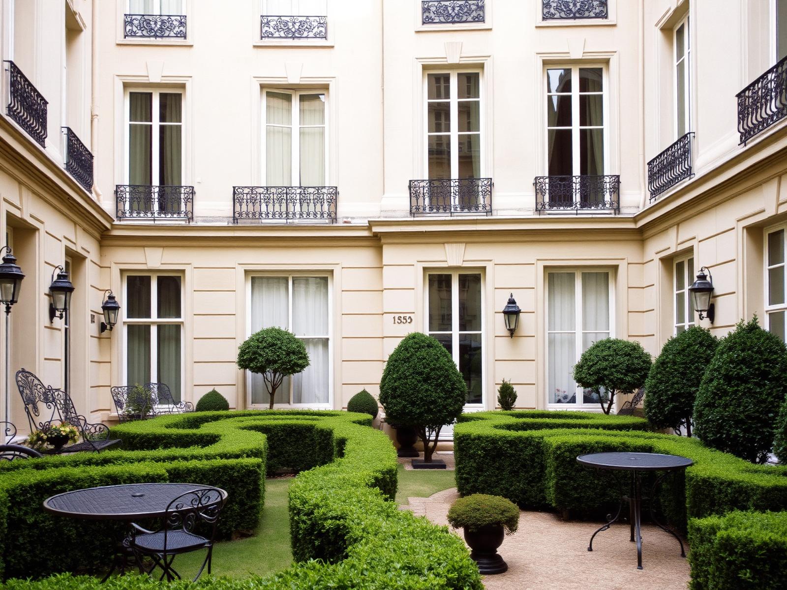 Innenhofgarten eines Pariser Stadthauses mit geschnittenen Buchshecken und heller Kalksteinfassade