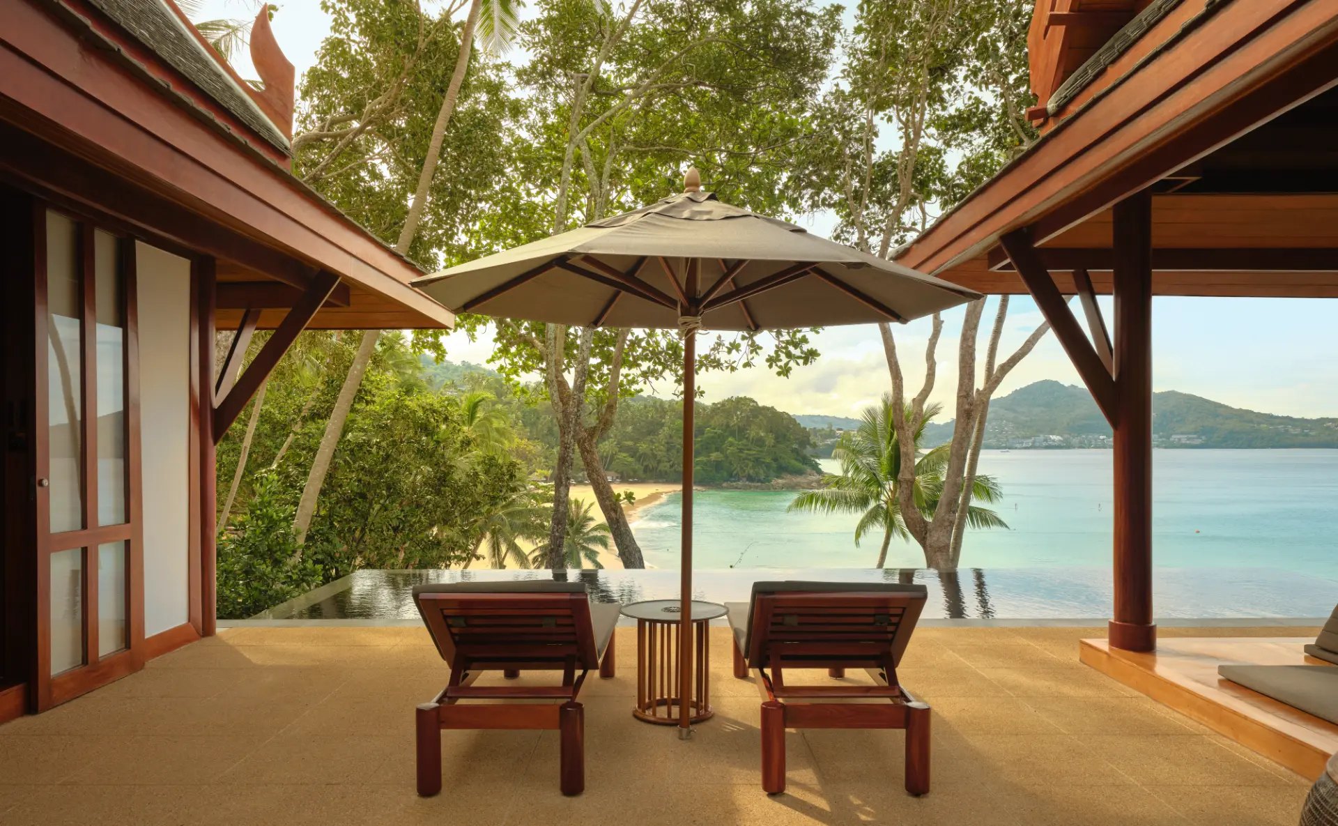 Terrasse eines Pavilions mit zwei Holzliegen unter einem Sonnenschirm, davor ein privater Pool und die Bucht von Pansea