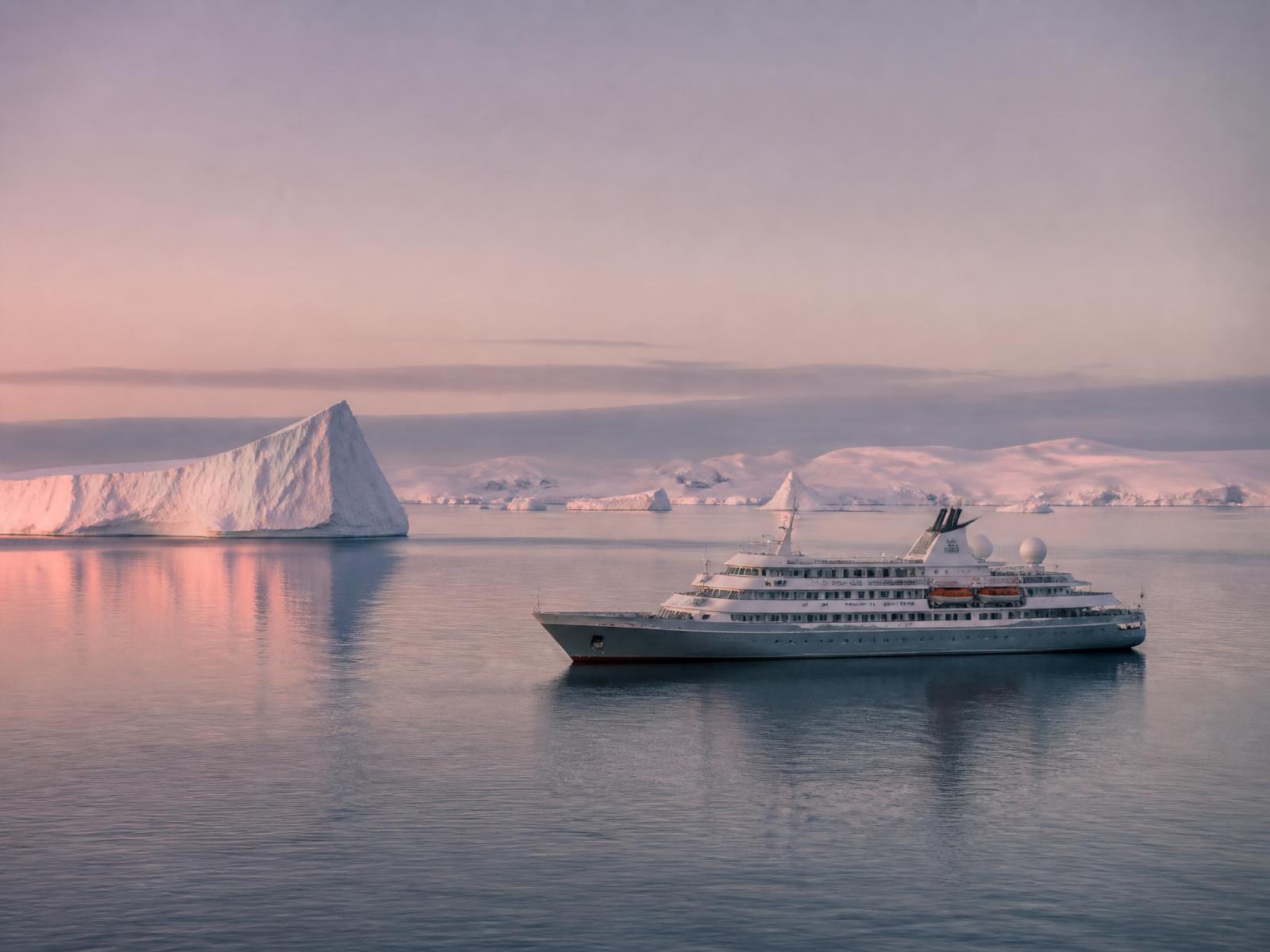 Small white expedition ship in polar waters at dawn beside pale icebergs in pink and grey light