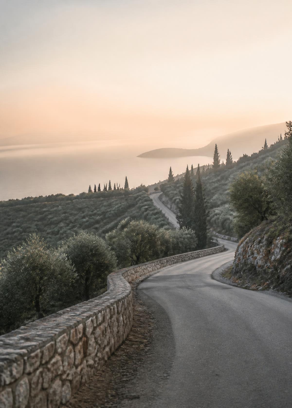 An empty terrace table set for one above a hazy landscape at golden hour