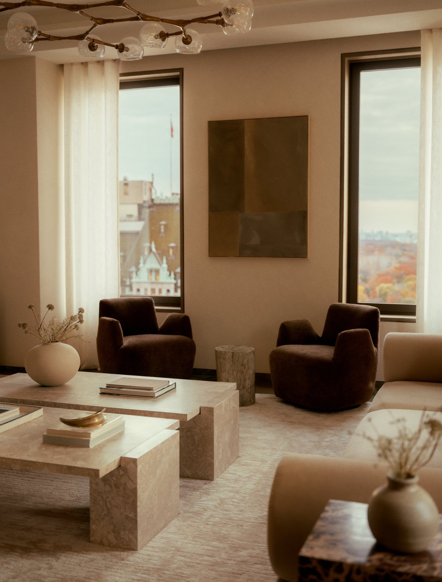 Sitzgruppe im Penthouse mit Travertintischen, Sesseln in dunklem Samt und Blick auf den herbstlichen Central Park